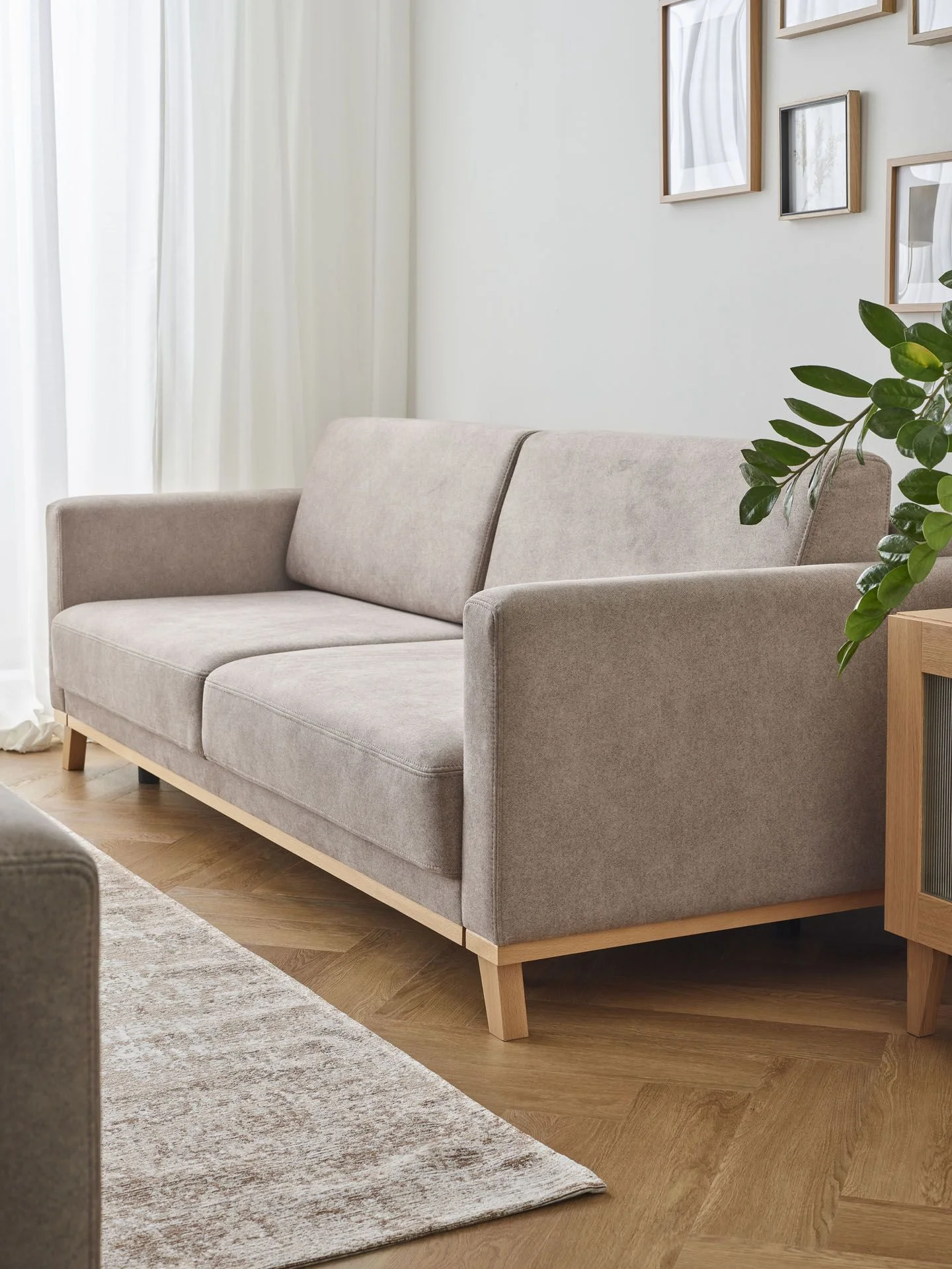 Minimalistyczny salon z beżową sofą na drewnianych nogach